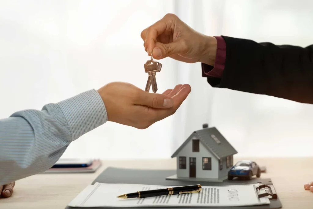 Une main qui tend des clés d'une maison à une autre main