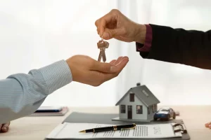 Une main qui tend des clés d'une maison à une autre main