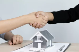 Deux personnes qui se sert la main avec une maison en dessous